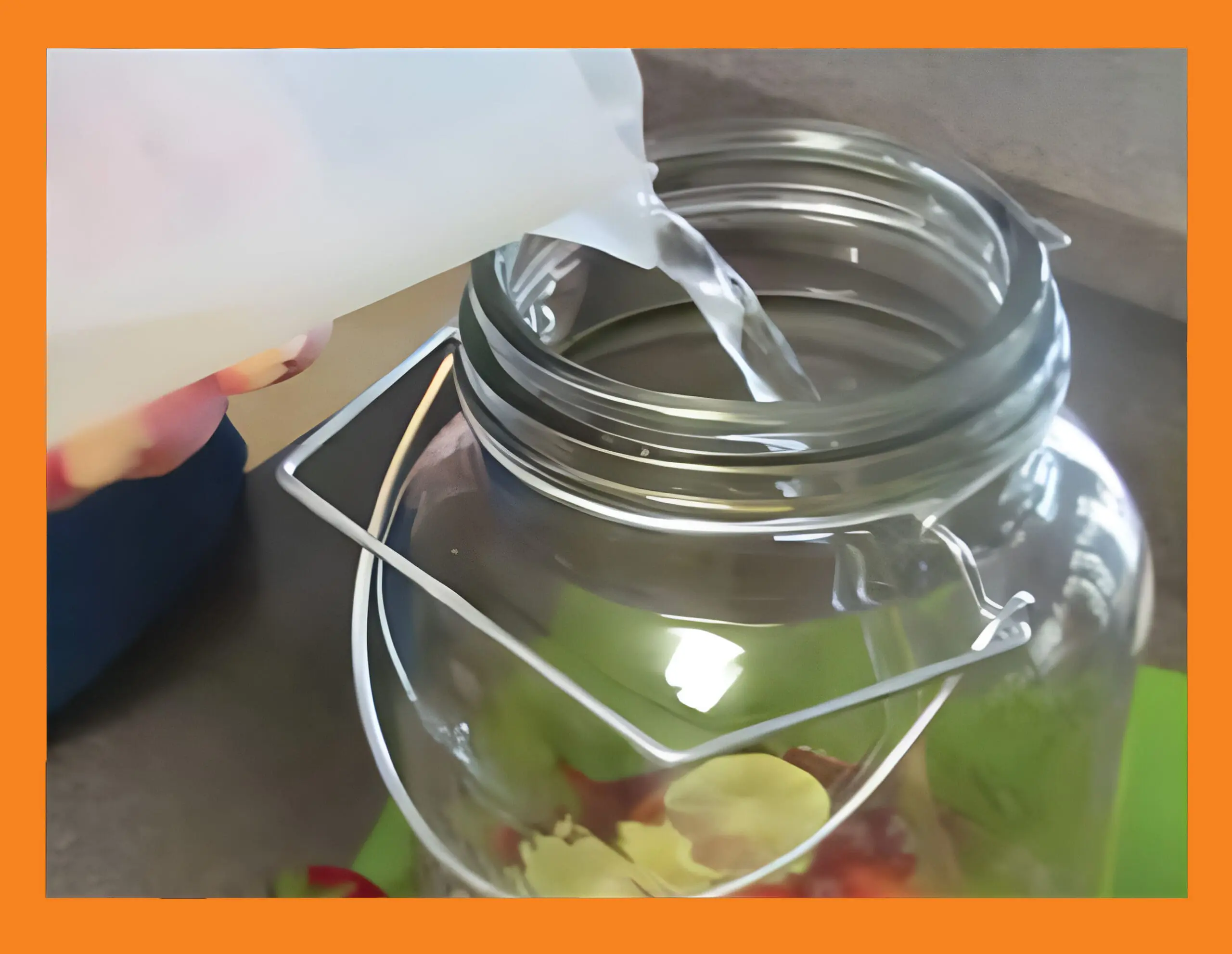 Water being poured into a glass jar with strawberries and lime slices.