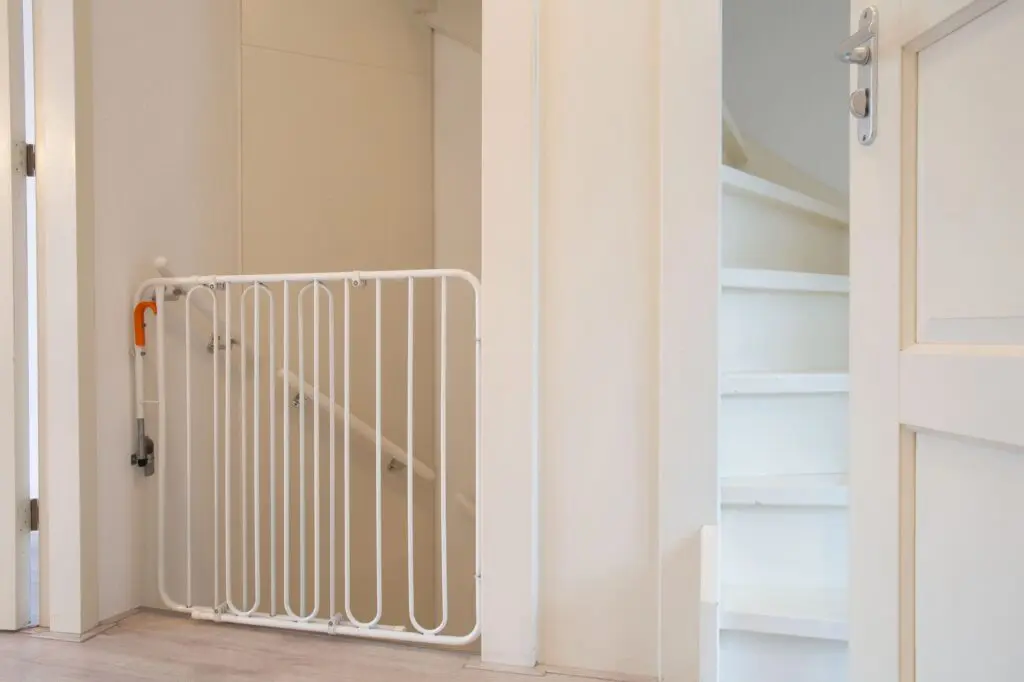 White safety gate in front of a staircase in a hallway.