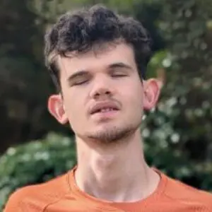 Gabe with eyes closed wearing an orange shirt outdoors