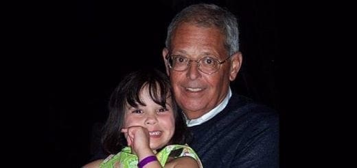 Man in glasses holding a young girl.
