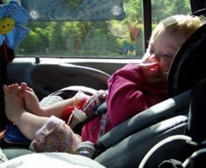 Baby in a car seat with a toy attached to the window.