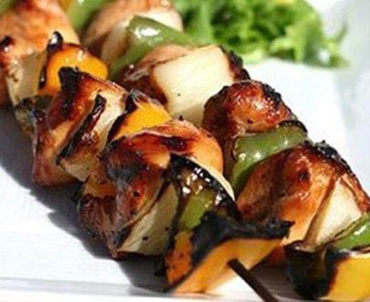 Chicken and vegetable skewers on a white plate.