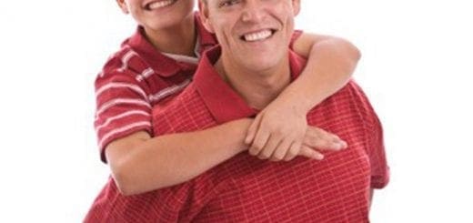 A smiling father gives his son a piggyback ride.
