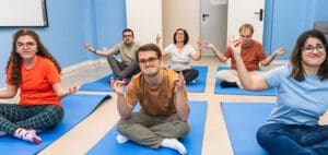 People practicing yoga in a classroom with blue walls.