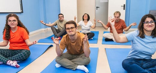 People practicing yoga in a classroom with blue walls.