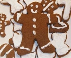 A gingerbread man cookie surrounded by other holiday-shaped cookies.
