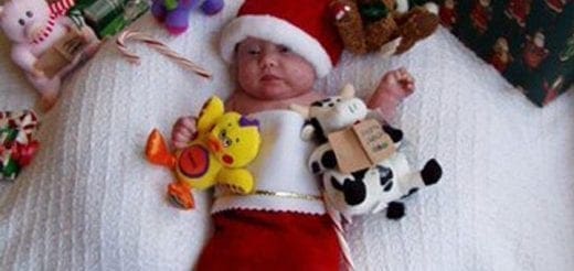 Baby in a Santa hat and stocking surrounded by Christmas toys.