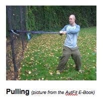 Man pulls a thick rope attached to a fence in a park setting.