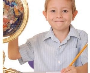 Young boy smiling while holding a globe and pencil.
