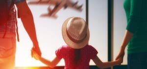 Family holding hands and looking at an airplane taking off.