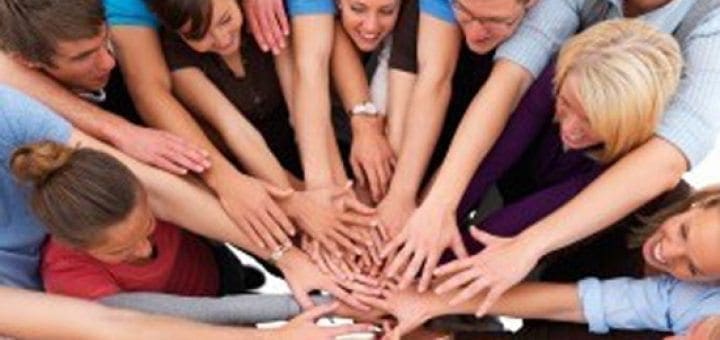 Diverse group of people with hands clasped together in the center.
