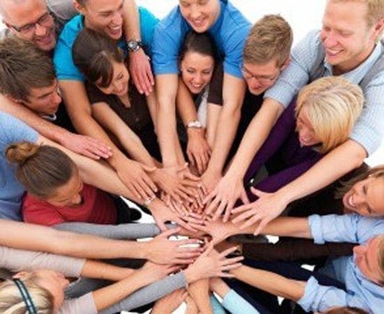 Diverse group of people with hands clasped together in the center.