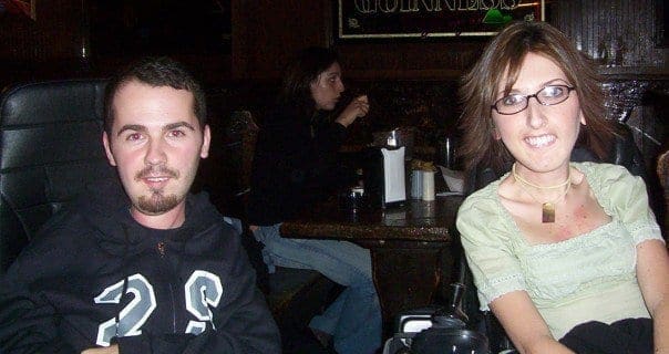 A man and a woman sit in a dimly lit room.