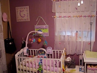 Nursery room with a white crib, mobile, and decorated walls.