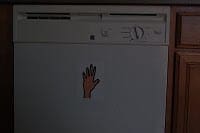 White dishwasher with a handprint sticker on its door.