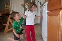 Two young children in a kitchen near a stove.