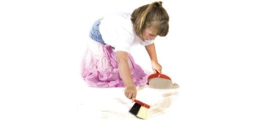 Young girl sweeping with a dustpan and brush.