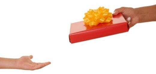A hand holds a red gift with a yellow bow over an outstretched hand.