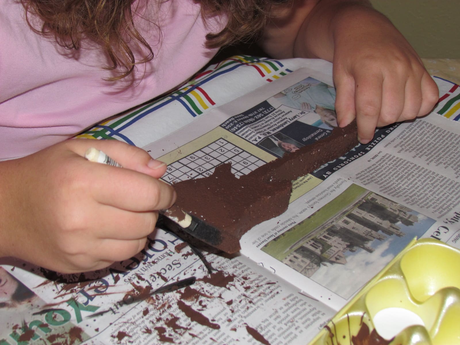 Child decorating a chocolate guitar craft with a brush.