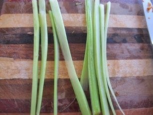 Celery stalks and cut pieces on a wooden cutting board