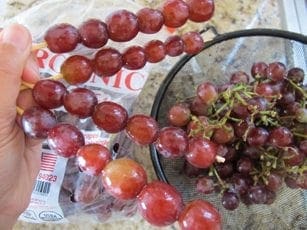 Grapes threaded onto wooden skewers next to a bowl of grapes.