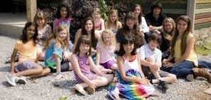 Group of children sitting outdoors on gravel.