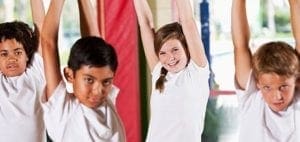 Four children in white shirts with arms raised.