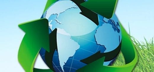 Recycling symbol surrounds a globe with green grass on the right.