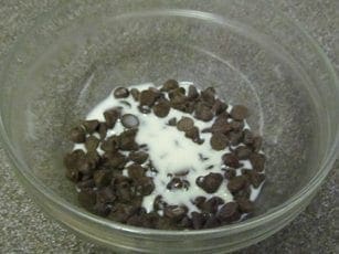 Chocolate chips and milk in a glass bowl for fondue.