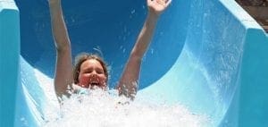 Child with arms raised going down a water slide