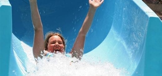 Child with arms raised going down a water slide
