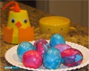 Colorful tissue paper Easter eggs on a plate with a chick craft in the background.