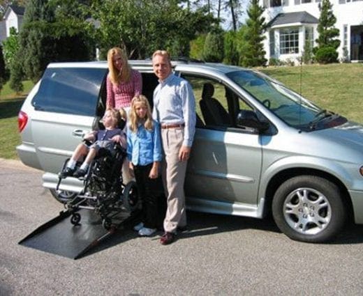 Family with a child in a wheelchair next to a van with a ramp.