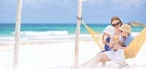 Woman with two children in a hammock on a beach.