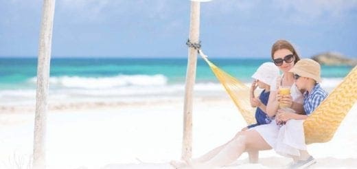 Woman with two children in a hammock on a beach.
