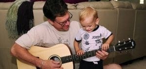 Man and child playing acoustic guitar together.