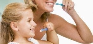 Woman and child brushing their teeth together.