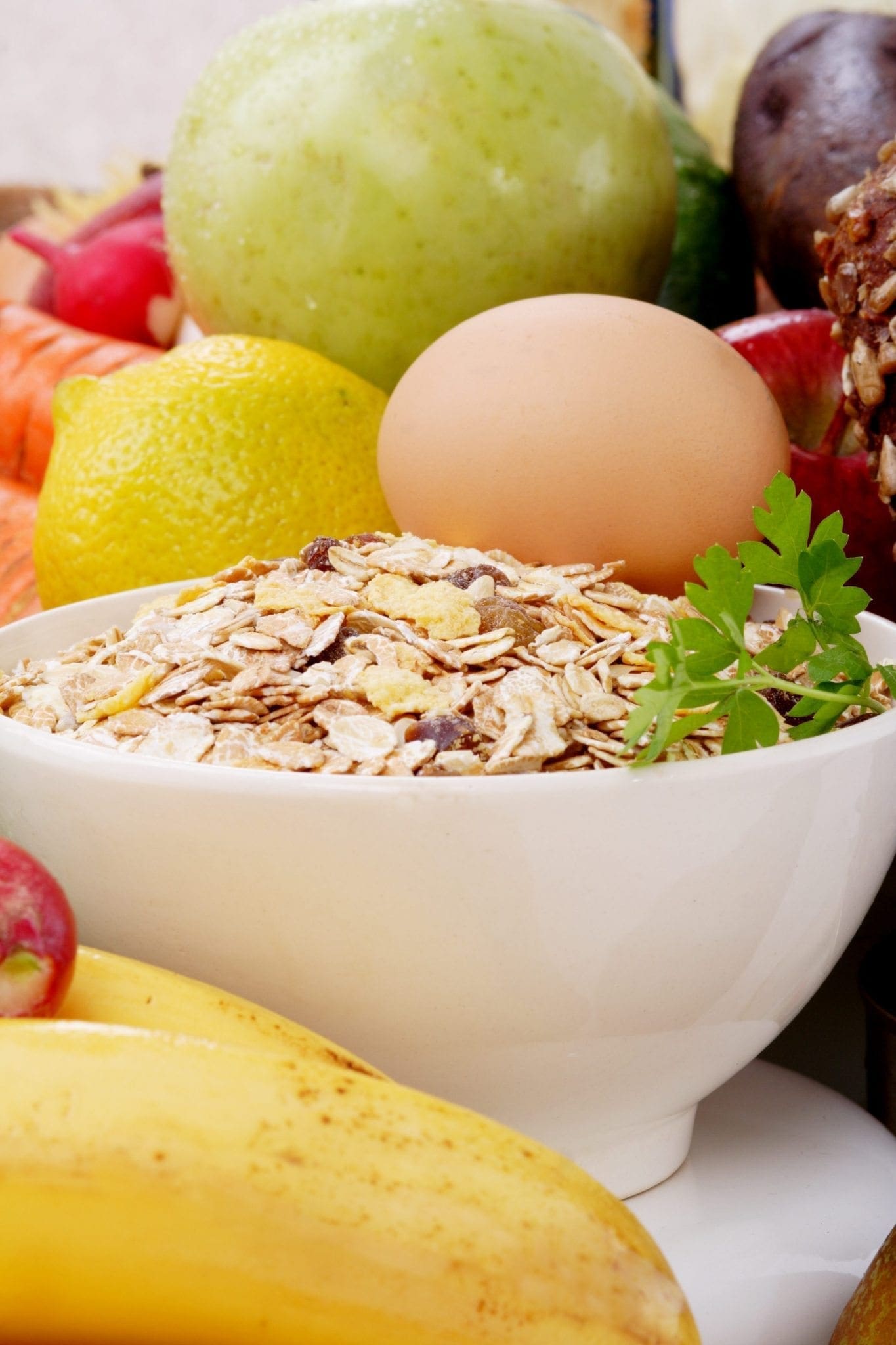 Bowl of oatmeal with an egg and various fruits and vegetables.