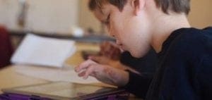 Young boy using a tablet at a table.
