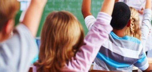 Children with hands raised in a classroom