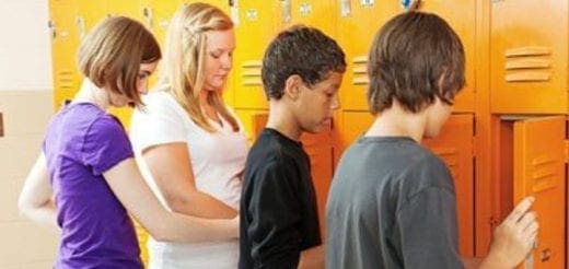Students stand in front of orange lockers at a middle school.