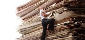Woman climbing a huge stack of papers.
