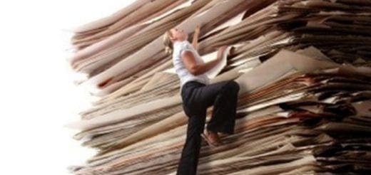 Woman climbing a huge stack of papers.