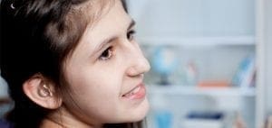 Young woman with a hearing aid smiles.