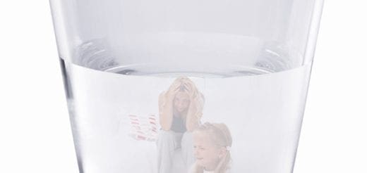 Two blurred figures, one adult and one child, are visible through a glass of water.