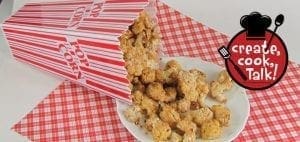 Cheesy" cauliflower popcorn spills out of a popcorn box onto a plate.