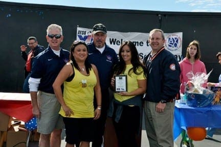Four adults stand together in front of a banner that reads "Welcome to AYSO VIP Soccer.