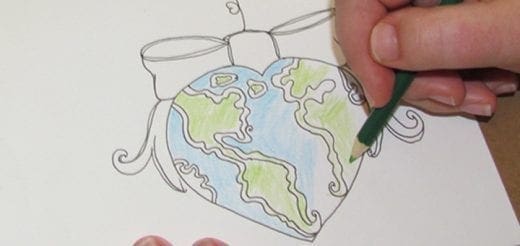 Hand coloring a heart-shaped globe with a green pencil.