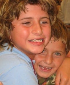 Two young siblings embrace in a warm, close-up portrait.