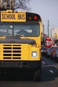 Yellow school bus with its stop sign extended, signaling the upcoming transition back to the school routine.